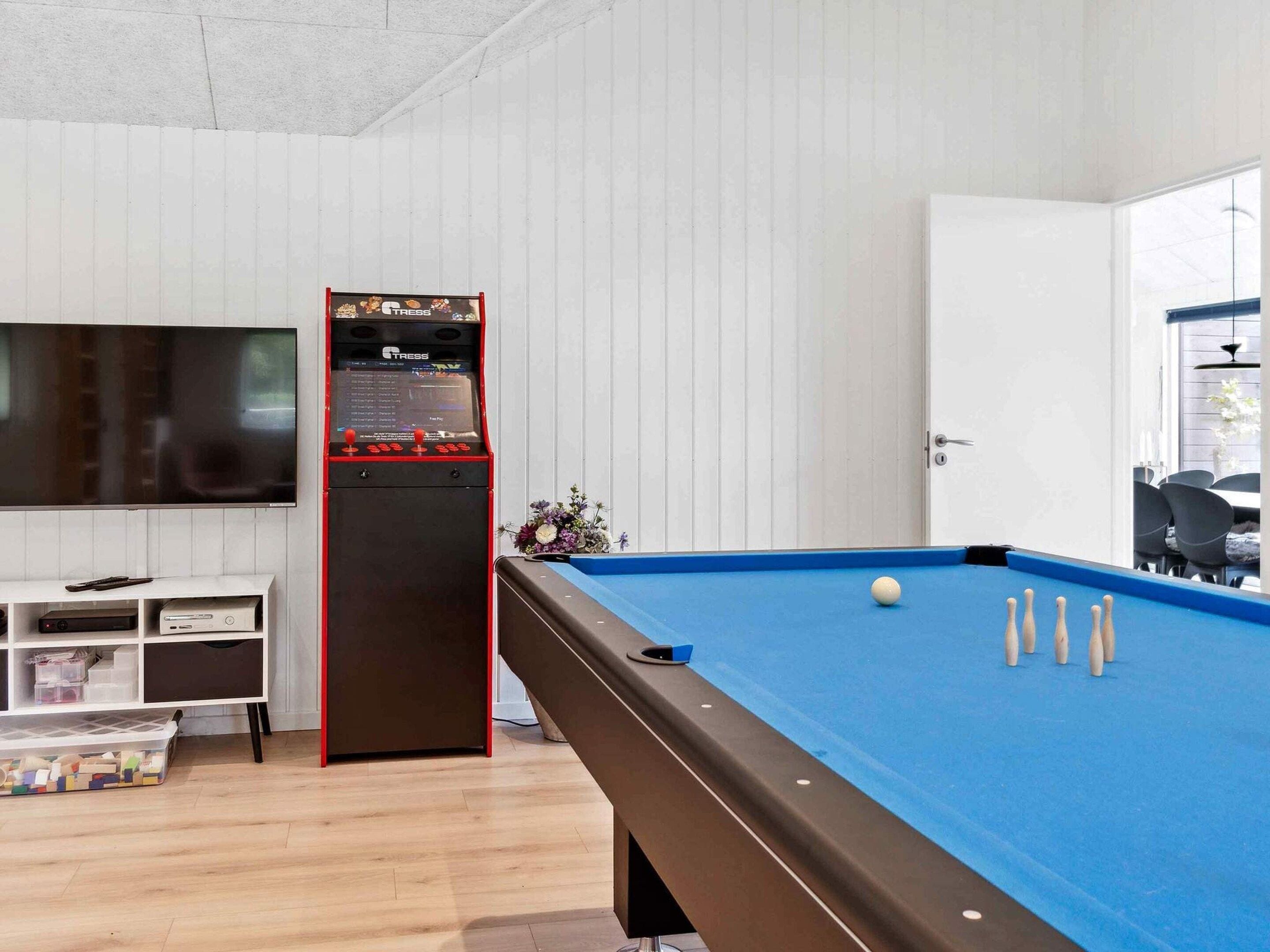 Une table de billard recouverte d’un drap bleu, un queue de billard et plusieurs billes blanches.