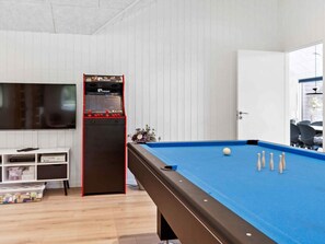 Een pooltafel met een blauwe viltkleed, een keu en verschillende witte poolballen.