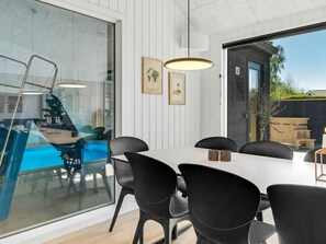 A modern dining area with a glass partition, a pool, and a wooden deck. - 5 Star Holiday Home in Dronningmolle (Dronningmolle)