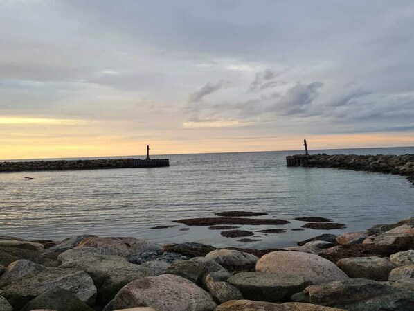 A coastal scene with a rocky shoreline, calm water, and two distant lighthouses. - 5 Star Holiday Home in Dronningmolle (Dronningmolle)