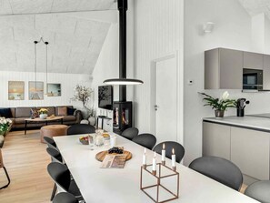 A modern living room with a fireplace, dining area, and kitchen. - 5 Star Holiday Home in Dronningmolle (Dronningmolle)