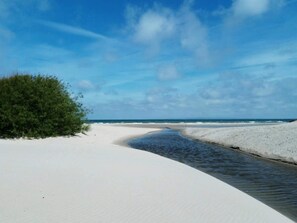 A beach with white sand, a narrow water channel, and a clear blue sky. - 5 Star Holiday Home in Dronningmolle (Dronningmolle)