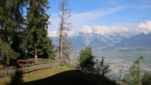 A mountainous landscape with a clear view of a town below, a picnic table, and a wooden fence. - Radiant Apartment Facing Hills (Veysonnaz)