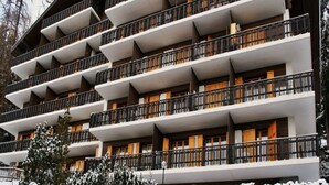 A multi-story hotel with balconies, wooden railings, and a snowy landscape. - Radiant Apartment Facing Hills (Veysonnaz)