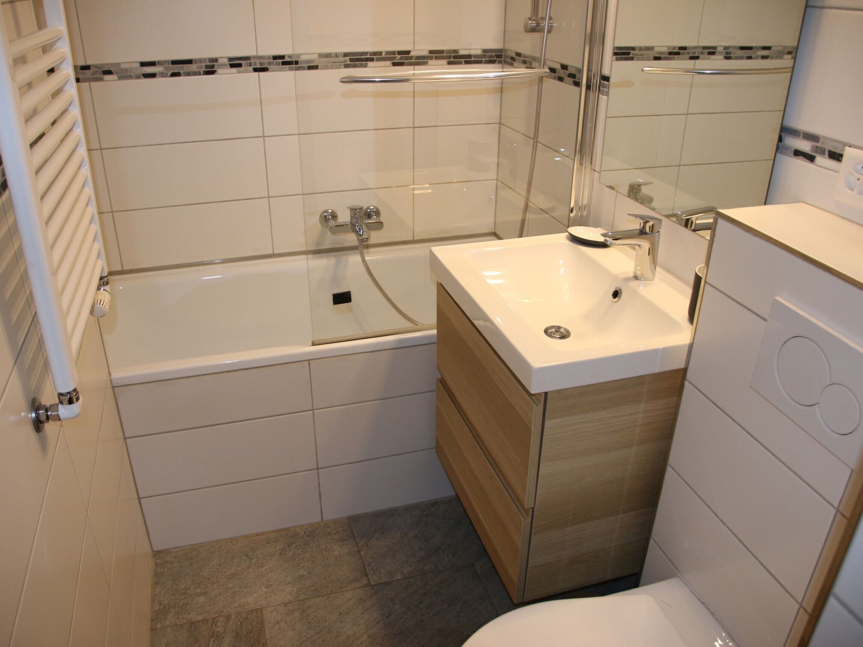 A modern bathroom with a bathtub, a sink, and a toilet.