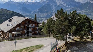 Eine Berglodge mit geneigtem Dach, mehreren Balkonen und Blick auf die umliegenden Berge.