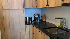 Eine Küche mit Holzausstattung, einer Kaffeemaschine, einem Wasserkocher und einem Spülbecken.