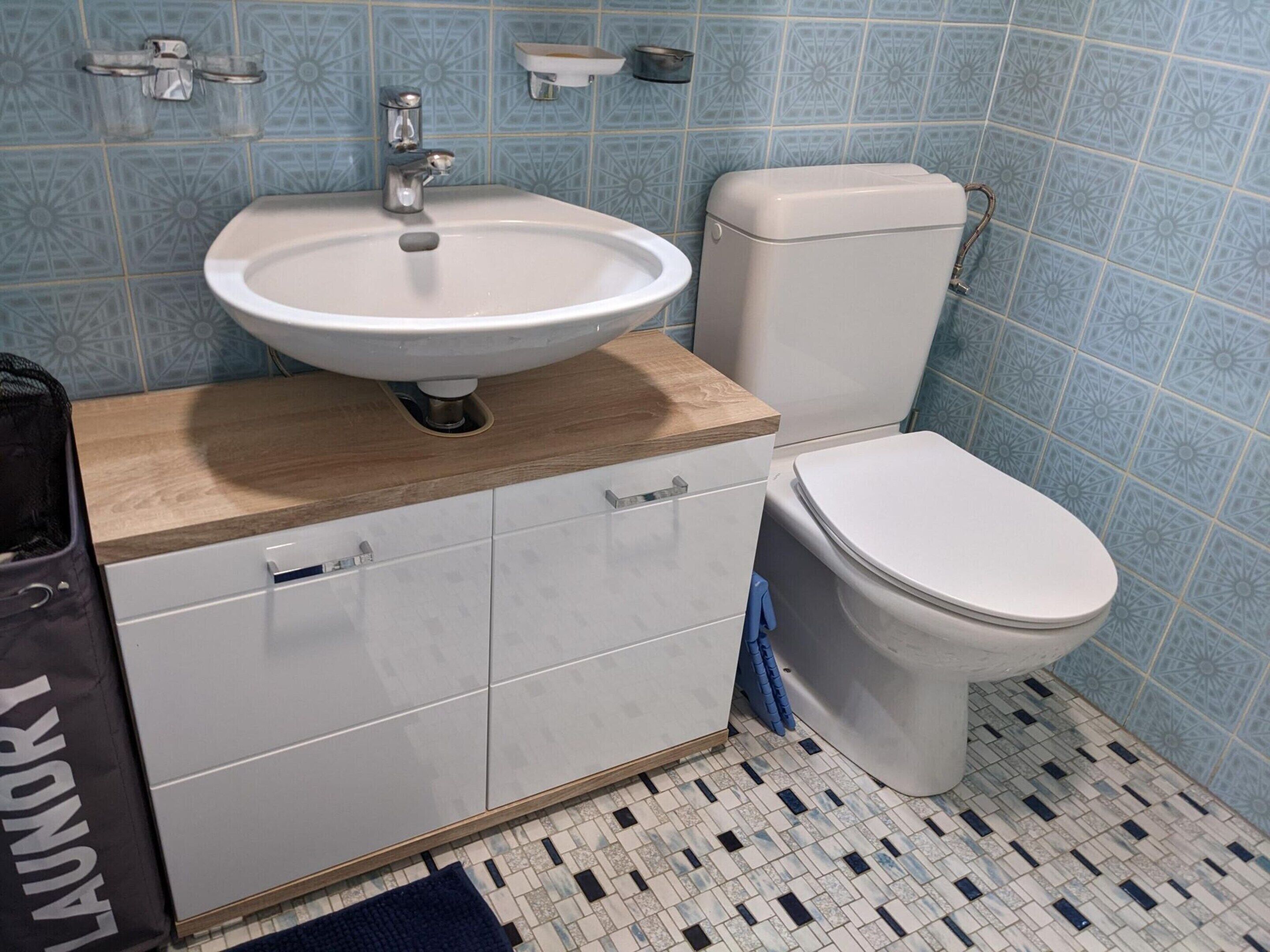 A bathroom with a sink, toilet, and cabinets.