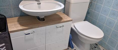 A bathroom with a sink, toilet, and cabinets.