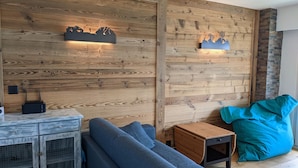 Ein modernes Wohnzimmer mit einer Holzwand, einem Sofa, einem kleinen Tisch und einem Sitzsack.