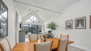 A dining area with a wooden table and chairs, a potted plant, and framed pictures on the wall. - Live the North Shore dream in this mountain-view penthouse! (North Vancouver)