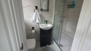 A bathroom with a glass shower enclosure, a white sink, a toilet, and a towel rack. - Private Room, Sleeps 2 with Ensuite & Parking (Birmingham)