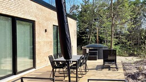 An outdoor patio with a table and chairs, a barbecue grill, and a covered seating area. - 5 Star Holiday Home in Vestervig (Vestervig)