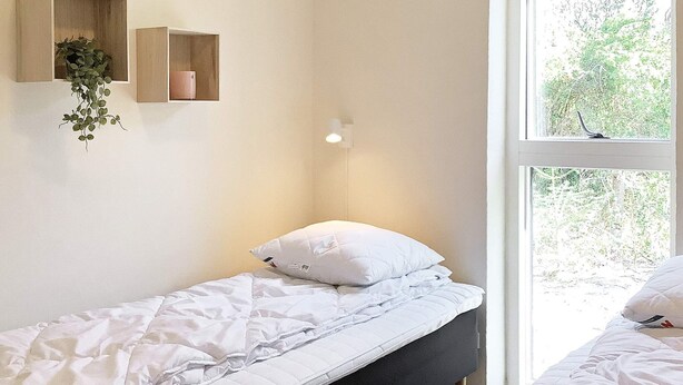 A single bed with white bedding, a bedside table, and a window with a view of greenery. - 5 Star Holiday Home in Vestervig (Vestervig)