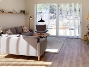A living room with a sofa, armchair, and a small table. There is a large sliding glass door leading to an outdoor area. - 5 Star Holiday Home in Vestervig (Vestervig)