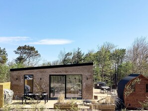 A modern outdoor living space with a brick exterior, large sliding glass doors, and a wooden deck area. - 5 Star Holiday Home in Vestervig (Vestervig)