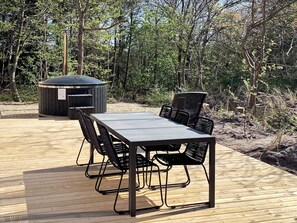 An outdoor deck with a rectangular table and four chairs, surrounded by a wooded area. - 5 Star Holiday Home in Vestervig (Vestervig)