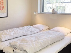 Una cama doble con ropa de cama blanca en una habitación con ventana.