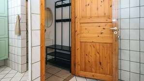 Een badkamer met een houten deur, een zwart metalen plank en een groen kastje.