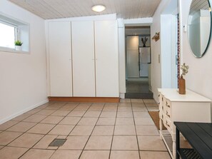 A room with a tiled floor, a white wardrobe, a bench, and a small table with a vase. - 6 Person Holiday Home in Ansager (Ansager)