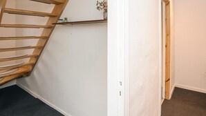 Een hoek van een kamer met een houten trap, een witte muur en een klein plankje met een plant.