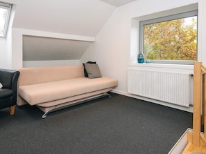 Una habitación con sofá, ventana y vistas a árboles, además de un radiador.