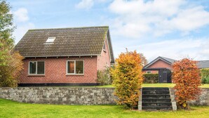 A brick house with a tiled roof, a stone wall, and a grassy yard. - 6 Person Holiday Home in Ansager (Ansager)