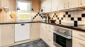 Una cocina moderna con armarios de madera, encimera negra, lavavajillas, microondas y estufa.