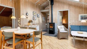 Un interior acogedor de madera con zona de comedor, sofá y chimenea.
