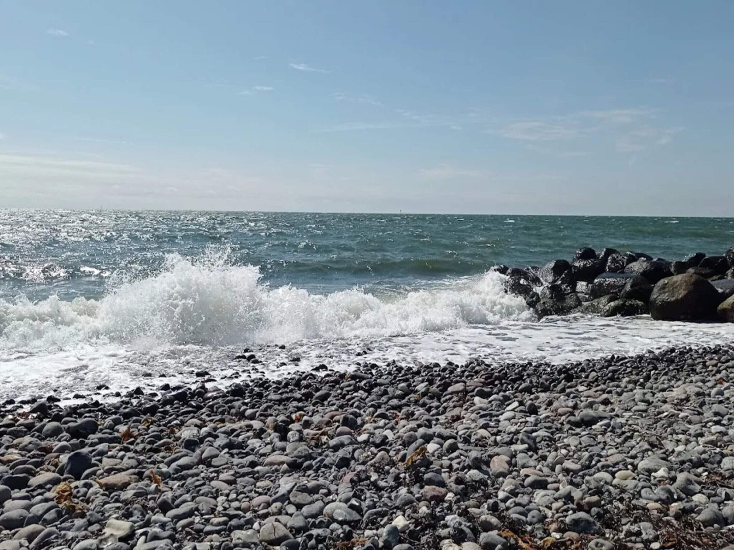 Ein felsiger Strand mit brechenden Wellen an großen Felsen.