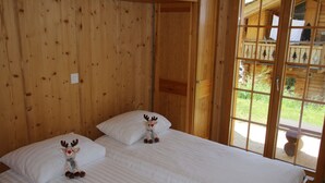 Een houten kamer met twee bedden, elk voorzien van een zacht rendiervriendje op de kussens.