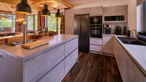 A modern kitchen with a central island, built-in appliances, and pendant lighting. - Welcoming Villa With Amenities (Trutnov)