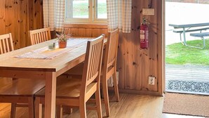 A wooden dining table with chairs, a potted plant, and a fire extinguisher mounted on the wall. - Spacious Holiday Home in Hoor (Hoor)