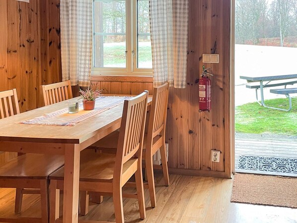 A wooden dining table with chairs, a potted plant, and a fire extinguisher mounted on the wall. - Spacious Holiday Home in Hoor (Hoor)