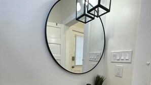 A bathroom with a white sink, a round mirror, and a potted plant. - Beautifully Restored! 3 Bedroom Home - 15 Min FQ! (New Orleans)