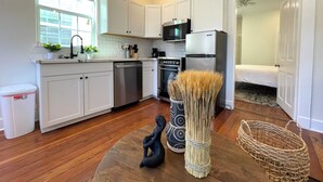 A modern kitchen with white cabinets, stainless steel appliances, a dishwasher, and a decorative vase. - Beautifully Restored! 3 Bedroom Home - 15 Min FQ! (New Orleans)