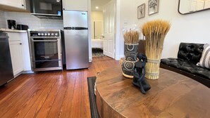 A modern kitchen with stainless steel appliances, a wooden floor, and a black sofa with a mirror. - Beautifully Restored! 3 Bedroom Home - 15 Min FQ! (New Orleans)