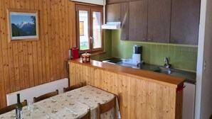 Una cucina compatta con pareti in legno, un piccolo angolo ristoro e una finestra con vista sulle montagne.