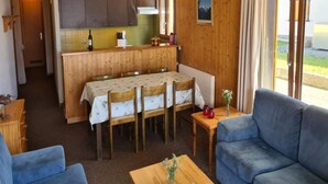 Una stanza accogliente con un tavolo da pranzo in legno, un divano blu e un angolo cottura con pensili e una finestra.