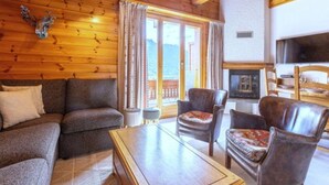Un accogliente soggiorno con pareti in legno, un divano, poltrone, un tavolino da caffè e un camino.