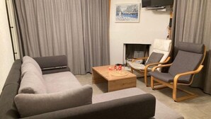 Una sala de estar moderna con un sofá seccional gris, dos sillones, una mesa de centro de madera y un televisor de pantalla plana montado en la pared.