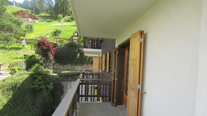 Un balcón con vistas a un paisaje verde y una casa al fondo.