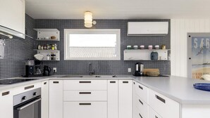 Una cocina moderna con armarios blancos, salpicadero de azulejos blanco y negro, y una ventana sobre el fregadero.