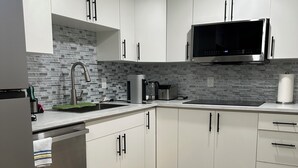 A modern kitchen with white cabinets, a stainless steel refrigerator, a microwave, and a coffee maker. - Cozy 1BR Suite at Winnipeg South (Winnipeg)