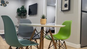 A modern kitchen with a dining table, four chairs, a TV, a plant, and a refrigerator. - Cozy 1BR Suite at Winnipeg South (Winnipeg)