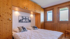 Una habitación con paneles de madera, una cama, un cuadro en la pared y una ventana.