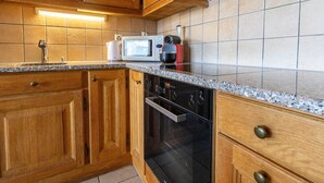 Una cocina con armarios de madera, microondas, cafetera y tostadora.