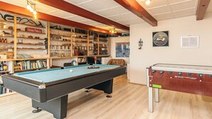 A billiards room with a pool table, a foosball table, and shelves with various items. - 16 Person Holiday Home in Vestervig (Vestervig)