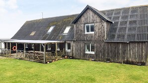 A large wooden building with a sloped roof, multiple windows, and a covered porch area. - 16 Person Holiday Home in Vestervig (Vestervig)