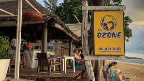 Un bar de platja anomenat "The Ozone" amb seients a l'aire lliure i una estructura de teules.